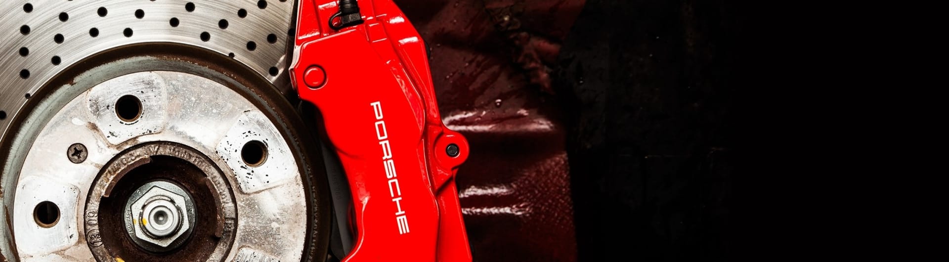 Roter Porsche-Bremssattel in Nahaufnahme während der Aufarbeitung