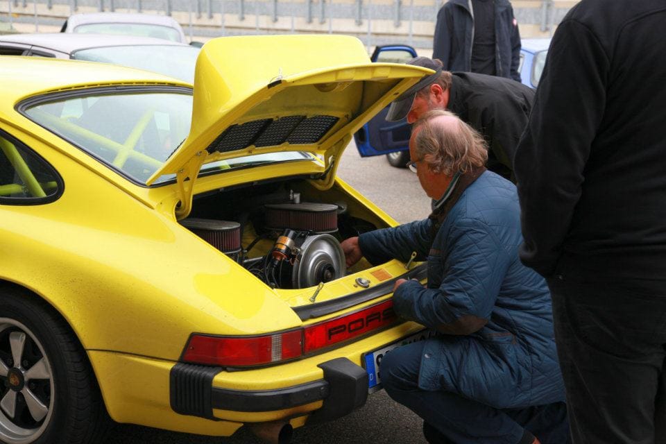 Motorcheck an einem gelben Porsche 911 im Fahrerlager, hauseigener Werkstatt-Service an der Strecke