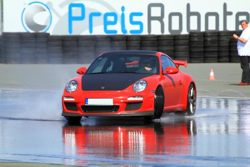 Roter Porsche 911 GT3 auf bewässerter Übungsfläche beim Lundtauto-Fahrtraining