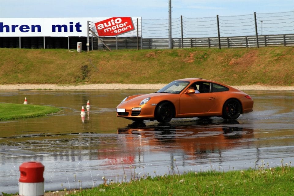 Porsche 911 beim Fahrtraining auf nasser Strecke